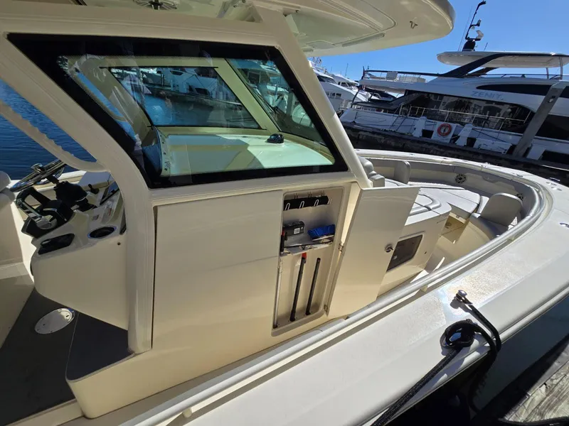 Slide: The Image of 2024 Scout 355 LXF boat docked, showcasing sleek design and spacious deck area. - 20