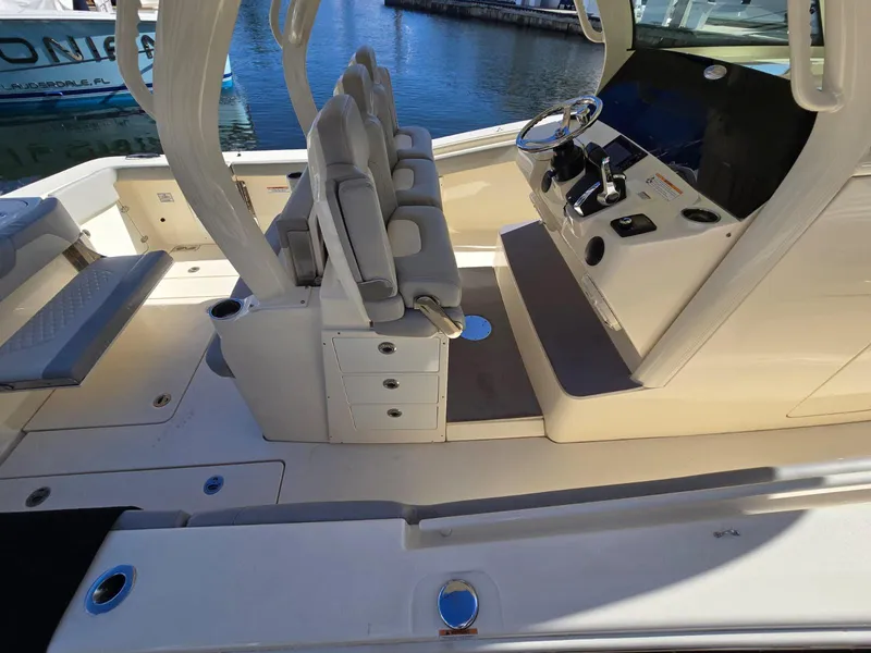 Slide: The Image of 2024 Scout 355 LXF boat interior with helm and seating, docked by the water. - 22