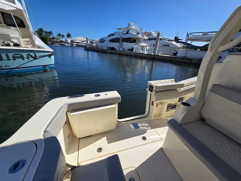 Slide: The Image of 2024 Scout 355 LXF boat docked in a marina with luxury yachts. - 23