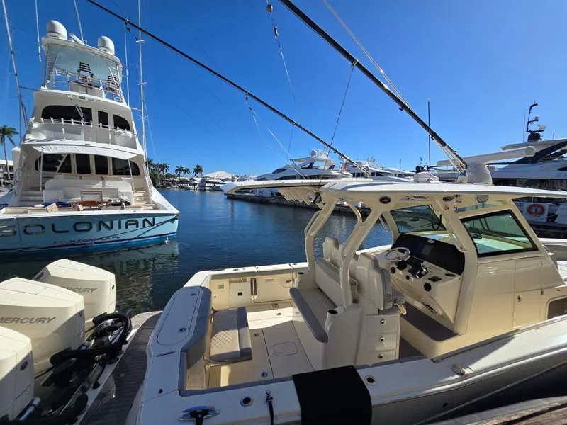Slide: The Image of 2024 Scout 355 LXF boat docked in a marina under clear blue skies. - 28