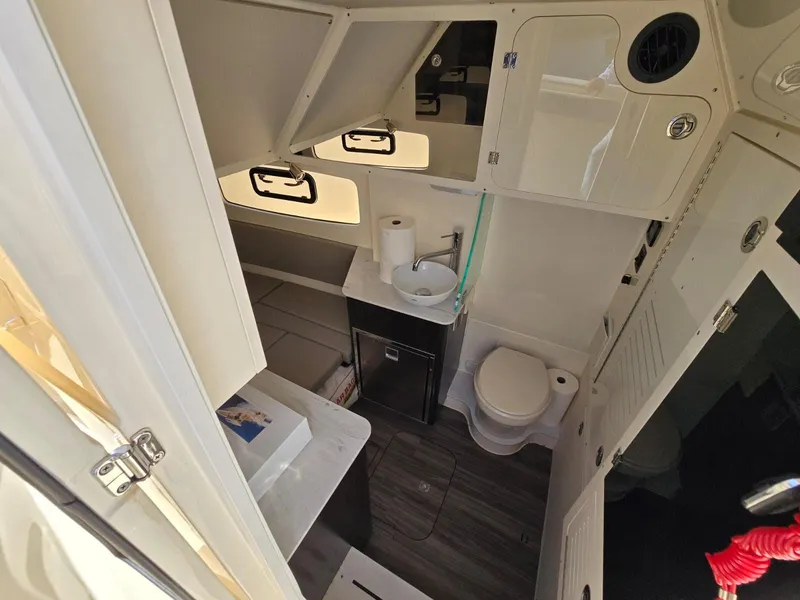 Slide: The Image of 2024 Scout 355 LXF boat bathroom with sink, toilet, and storage cabinets. - 31