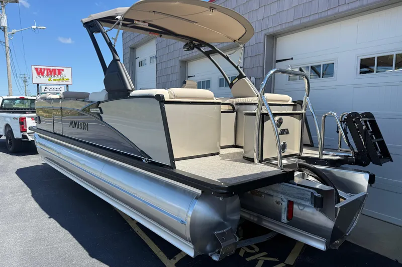 Slide: The Image of 2026 Avalon 2385 Catalina Quad Lounger Tri Toon boat with American flag, parked outdoors. - 7