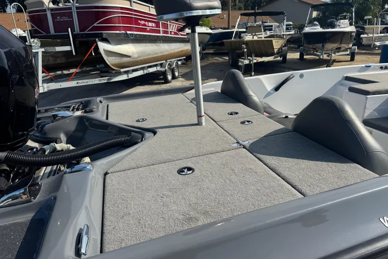 Slide: The Image of 2021 Bass Cat Margay boat interior with gray seating and deck, parked near other boats. - 19