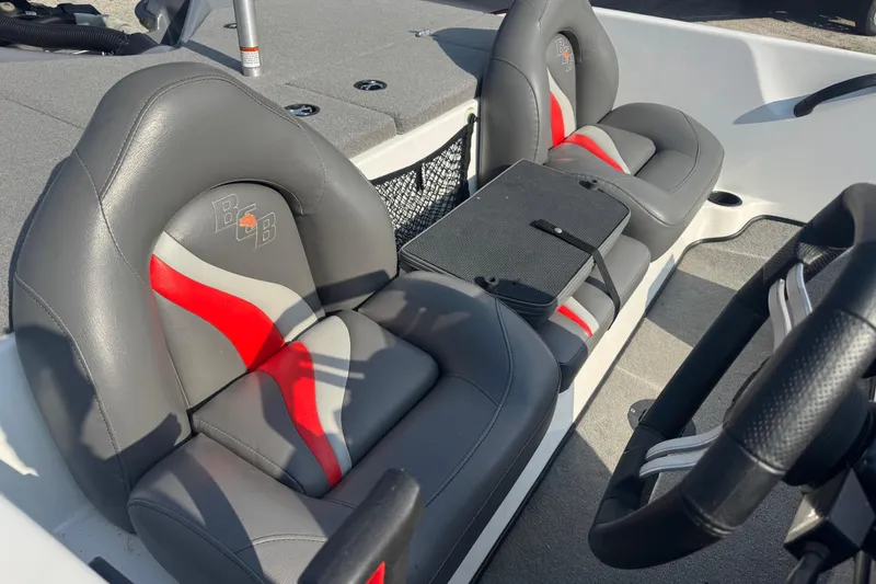 Slide: The Image of 2021 Bass Cat Margay boat interior with gray and red seats, steering wheel visible. - 24