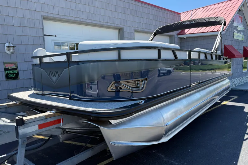 Slide: The Image of 2025 Avalon 2385 Venture 85 Tri Toon boat parked on a trailer outside a building. - 3