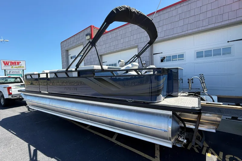 Slide: The Image of 2025 Avalon 2385 Venture 85 Tri Toon boat parked outside a garage. - 6