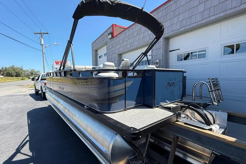 Slide: The Image of 2025 Avalon 2385 Venture 85 Tri Toon boat parked outside a garage. - 8