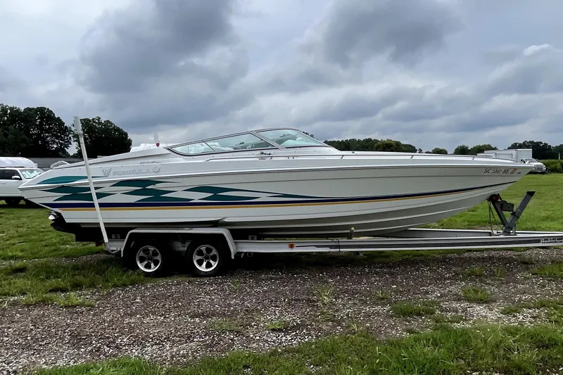 Slide: The Image of 1999 Formula 271 FASTech boat on trailer, parked on grassy area under cloudy sky. - 2
