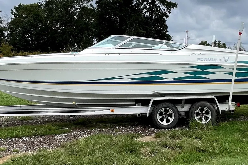 Slide: The Image of 1999 Formula 271 FASTech boat on trailer, parked on grass with trees in background. - 6