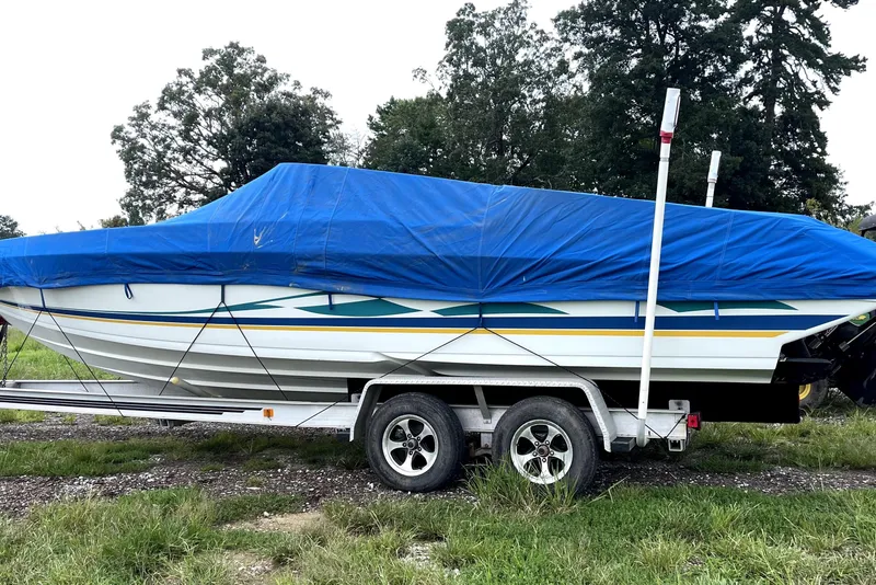 Slide: The Image of 1999 Formula 271 FASTech boat covered with blue tarp on a trailer, parked on grass. - 9