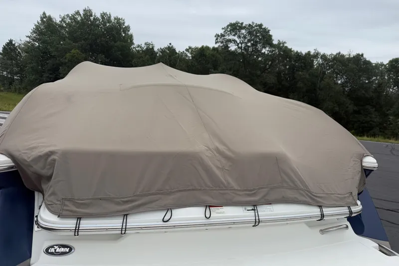 Slide: The Image of Covered 2007 Cobalt 232 boat with beige tarp, parked outdoors near trees. - 20