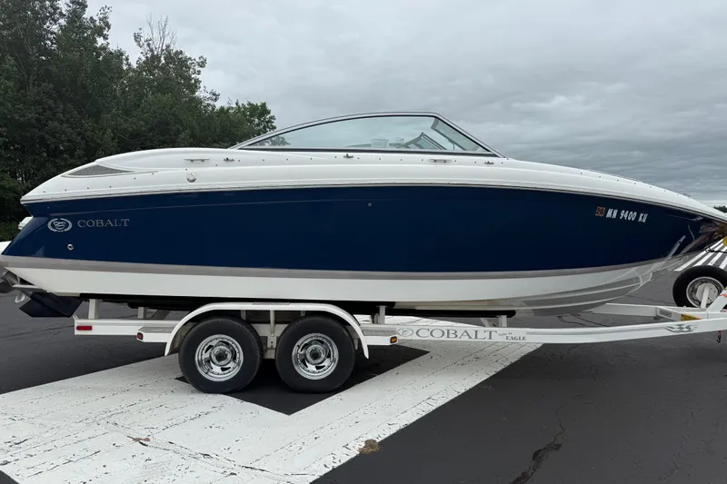 Slide: The Image of 2007 Cobalt 232 boat on trailer, blue and white design, parked outdoors. - 3