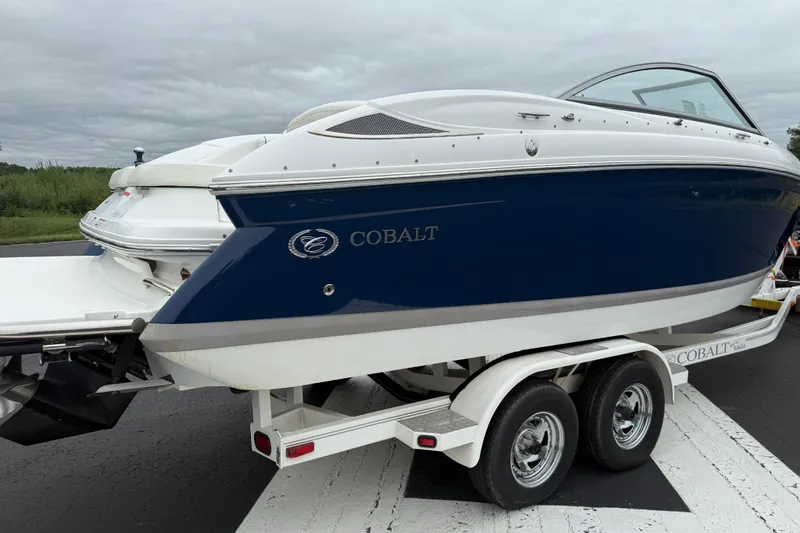 Slide: The Image of 2007 Cobalt 232 boat on trailer, blue and white design, parked on road. - 4