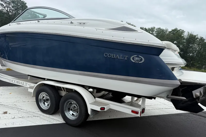 Slide: The Image of 2007 Cobalt 232 boat on trailer, blue and white design, parked outdoors. - 5