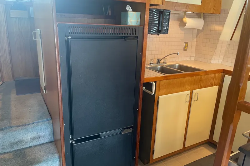 Slide: The Image of 1978 Delta Marine 43 Trawler kitchen with fridge, sink, and wooden cabinetry. - 35