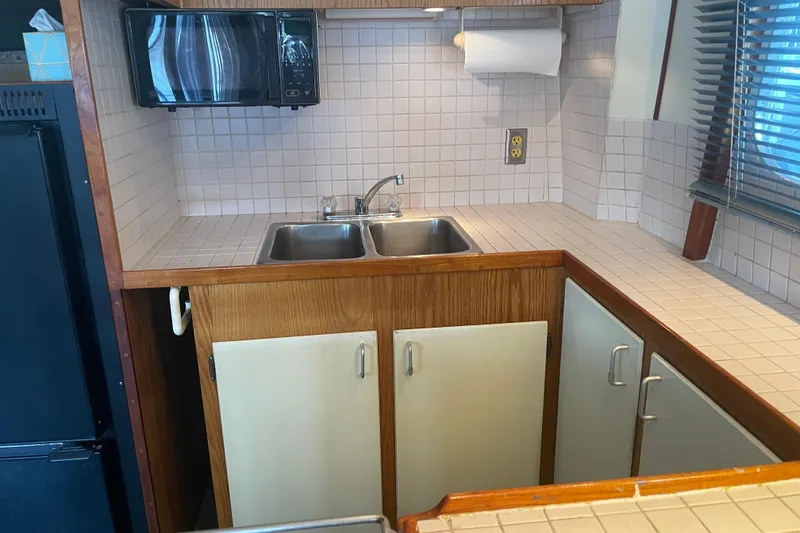 Slide: The Image of 1978 Delta Marine 43 Trawler kitchen with dual sink, microwave, and tiled countertops. - 37