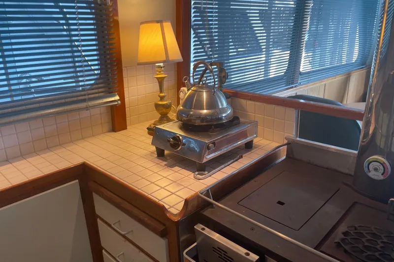 Slide: The Image of Cozy kitchen area on a 1978 Delta Marine 43 Trawler with stove and kettle. - 38
