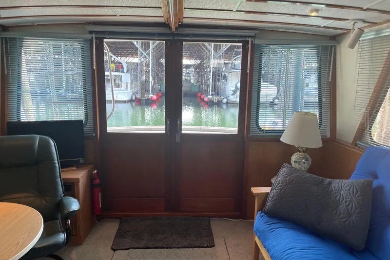 Slide: The Image of Interior of 1978 Delta Marine 43 Trawler with cozy seating and marina view. - 46