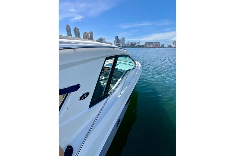 Slide: The Image of 2017 Sea Ray Sundancer 350 Coupe on calm water with city skyline backdrop. - 31