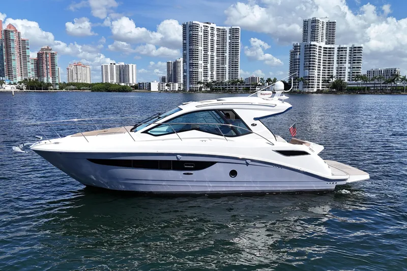 Slide: The Image of 2017 Sea Ray Sundancer 350 Coupe yacht on water with city skyline backdrop. - 8