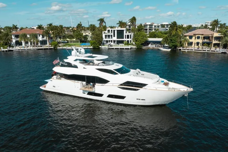 Slide: The Image of Luxurious 2018 Sunseeker 95 Yacht cruising on a scenic waterfront with palm trees. - 2