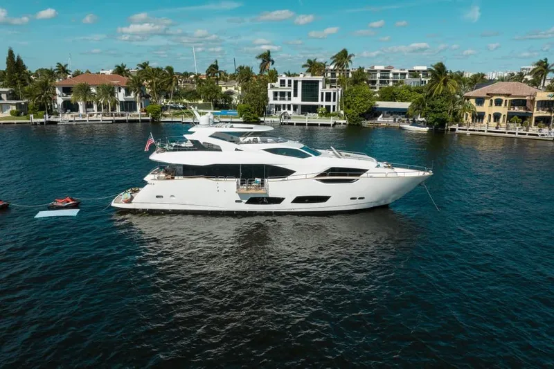 Slide: The Image of 2018 Sunseeker 95 Yacht on a serene waterfront with luxury homes in the background. - 3