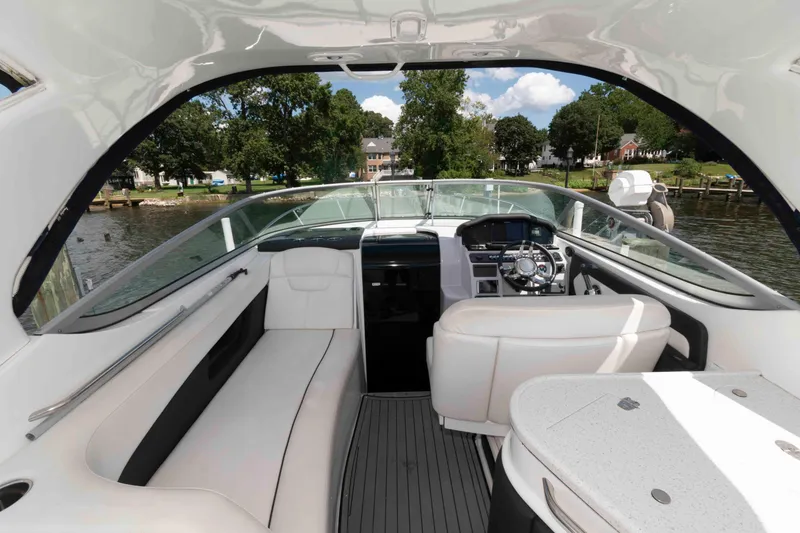 Slide: The Image of 2019 Rinker 290 EX boat interior with helm, seating, and water view. - 2