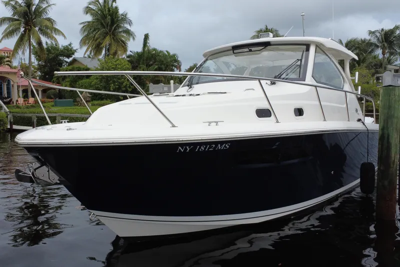 Slide: The Image of 2022 Pursuit OS 355 Offshore boat docked near palm trees. - 2