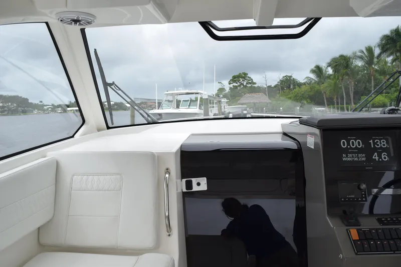 Slide: The Image of 2022 Pursuit OS 355 Offshore interior with white cushioned seating and stainless steel handle. - 234