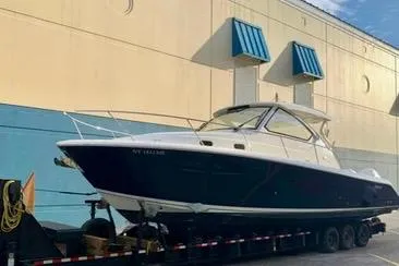 Slide: The Image of 2022 Pursuit OS 355 Offshore boat docked, front view with palm trees in background. - 3