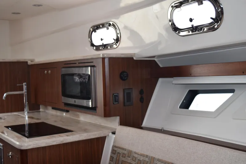 Slide: The Image of Interior of 2022 Pursuit OS 355 Offshore with polished wooden table and cushioned seating. - 434