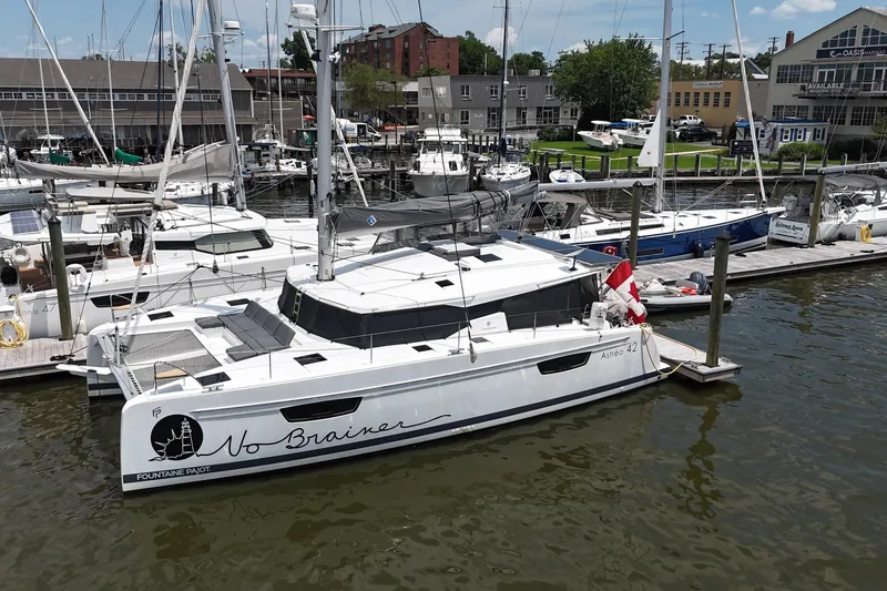 Slide: The Image of 2022 Fountaine Pajot Astrea 42 catamaran docked at a marina, featuring sleek design. - 2