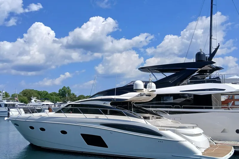 Slide: The Image of 2015 Princess V62-S yacht docked under a bright blue sky with clouds. - 1