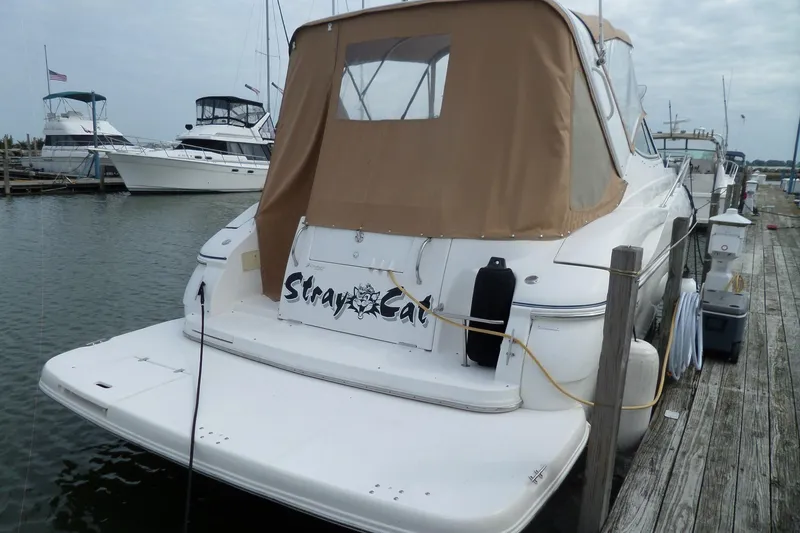 Slide: The Image of 2003 Cruisers Yachts 3275 Express docked, featuring tan canopy and "Stray Cat" name. - 2