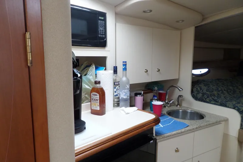 Slide: The Image of 2003 Cruisers Yachts 3275 Express interior kitchen with sink, microwave, and countertop items. - 32