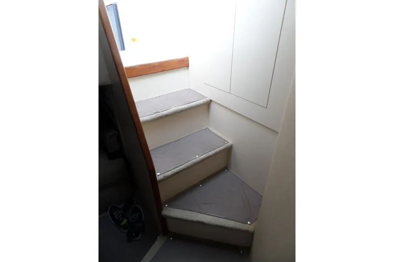 Slide: The Image of Interior stairs of 2003 Cruisers Yachts 3275 Express, featuring carpeted steps and wooden trim. - 49