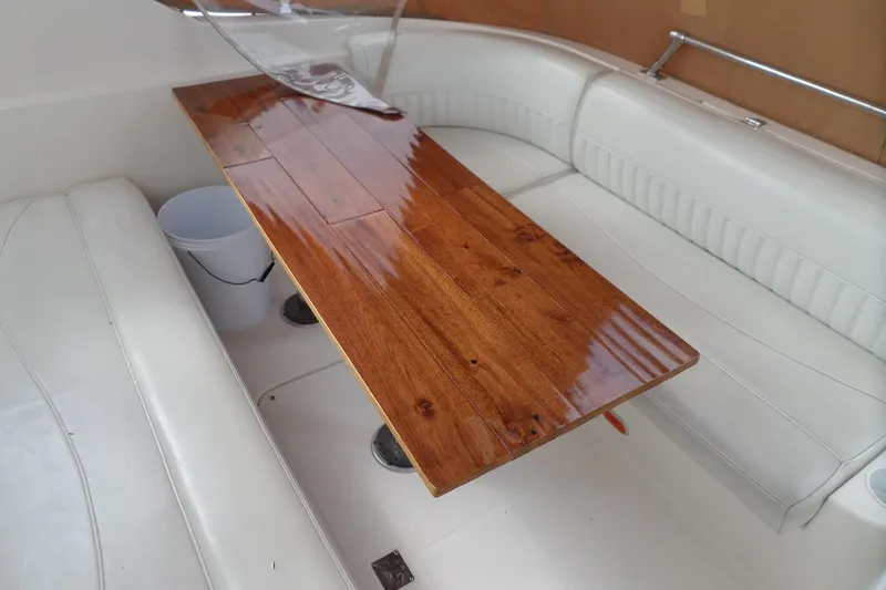 Slide: The Image of 2003 Cruisers Yachts 3275 Express interior with polished wooden table and white seating. - 8