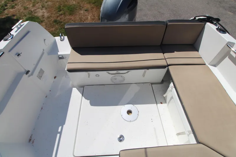 Slide: The Image of 2017 Jeanneau NC Sport 695 boat seating area with beige cushions and storage compartment. - 8