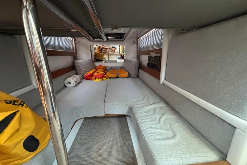 Slide: The Image of 2020 Axopar 28 Cabin Aft Cabin interior with gray seating and life jackets. - 19