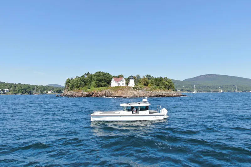 Slide: The Image of 2020 Axopar 28 Cabin Aft Cabin boat cruising near scenic island with lighthouse. - 2