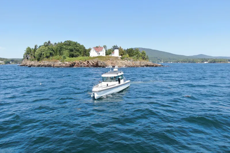 Slide: The Image of 2020 Axopar 28 Cabin boat cruising near scenic island with lighthouse. - 3