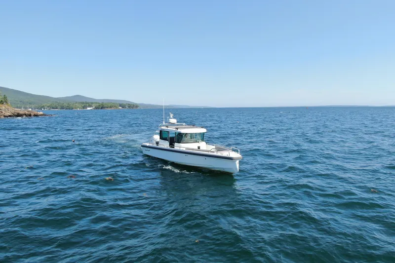 Slide: The Image of 2020 Axopar 28 Cabin Aft Cabin cruising on open water, scenic coastal backdrop. - 4