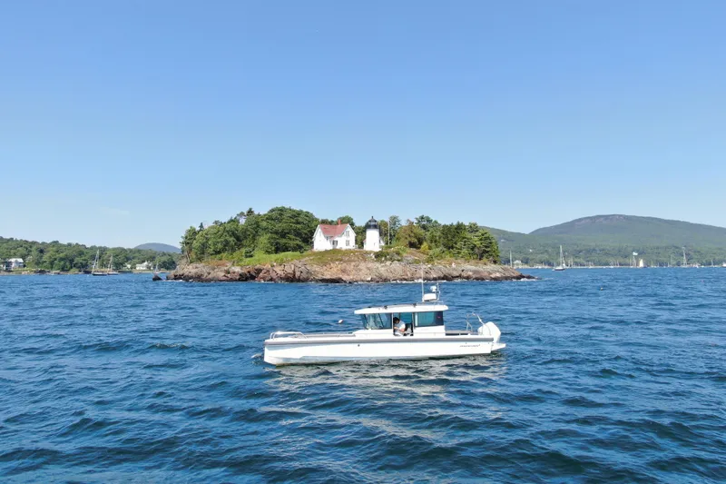 Slide: The Image of 2020 Axopar 28 Cabin Aft Cabin boat cruising near scenic island with lighthouse. - 7