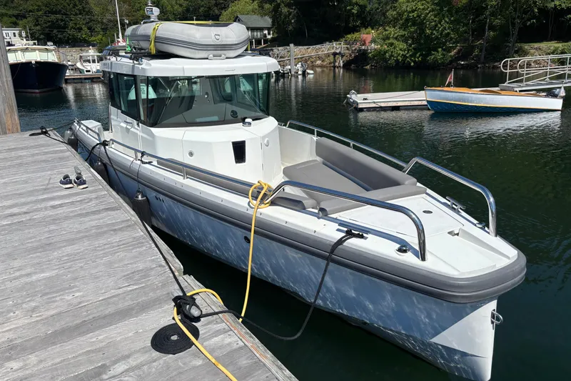 Slide: The Image of 2020 Axopar 28 Cabin Aft Cabin boat docked in a serene marina setting. - 9
