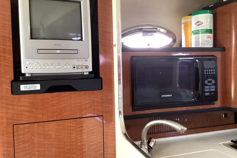 Slide: The Image of 2004 Sea Ray 280 Sundancer interior with TV, microwave, and sink. - 11