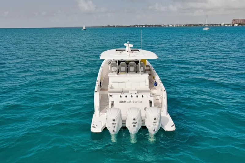 Slide: The Image of 2023 Regal 38 SAV boat on turquoise ocean, rear view with four engines. - 2