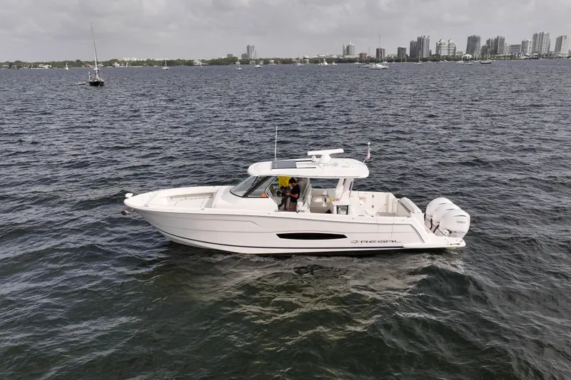 Slide: The Image of 2023 Regal 38 SAV boat cruising on a calm sea near a city skyline. - 3