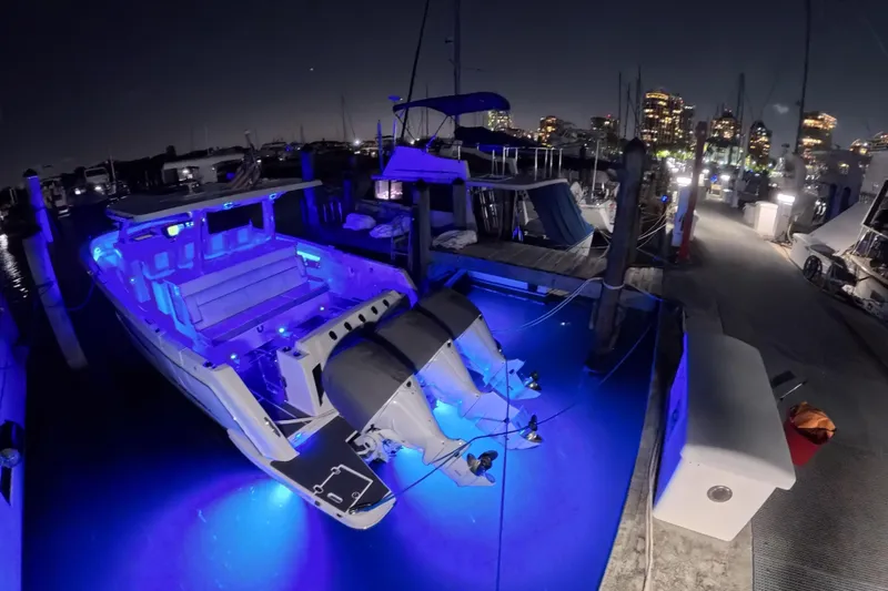 Slide: The Image of 2023 Regal 38 SAV boat illuminated with blue lights at a marina during nighttime. - 40