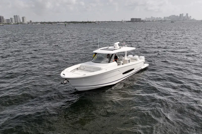 Slide: The Image of 2023 Regal 38 SAV boat cruising on open water with city skyline in background. - 6