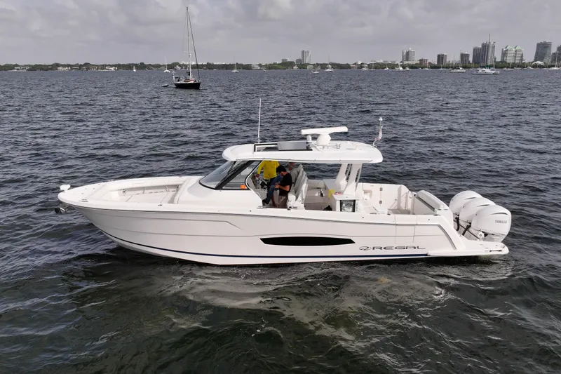 Slide: The Image of 2023 Regal 38 SAV boat cruising on a calm sea with city skyline in background. - 9